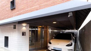 Un Tesla blanco estacionado en un área de estacionamiento techada, con un edificio moderno al fondo.