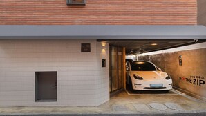 Un edificio moderno con fachada de baldosas blancas y un estacionamiento.