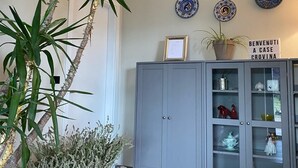 A room with a grey cabinet containing decorative items, a potted plant, and a sign that reads "BENVENUTI A CASE CROVINA". - Houses Crovina, large apartment with swimming pool in the hills (Emilia-Romagna)