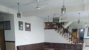 A spacious living area with a large sectional sofa, a coffee table, and a patterned rug. A staircase with wooden railings is visible in the background. - Hotel AL-Habib  (Islamabad)