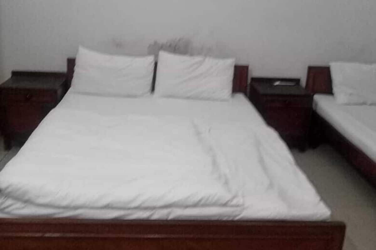 Habitación estándar de hotel con una cama individual, dos mesitas de noche y un equipo de aire acondicionado en la pared.
