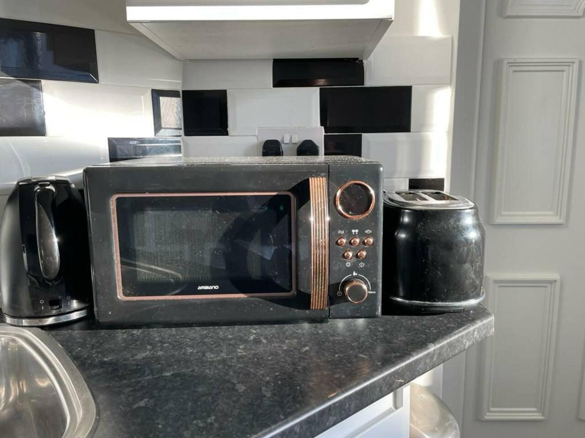 A kitchen with a black microwave, a toaster, and a coffee maker on the counter.