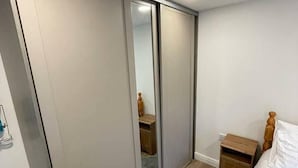 Ein Schlafzimmer mit großem Kleiderschrank, Nachttisch und flauschigem Teppich.