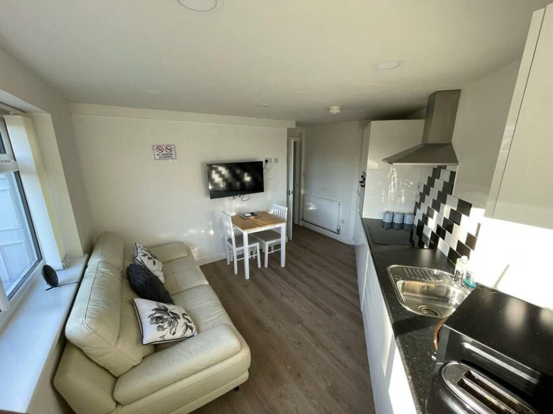 A compact living space with a sofa, a dining table, a TV, and a kitchenette.