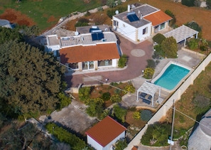 Vue aérienne d’une propriété résidentielle dotée d’une piscine, de panneaux solaires et d’un jardin.