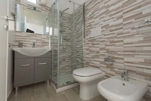 Une salle de bain moderne avec une douche à parois de verre, des toilettes et un lavabo.