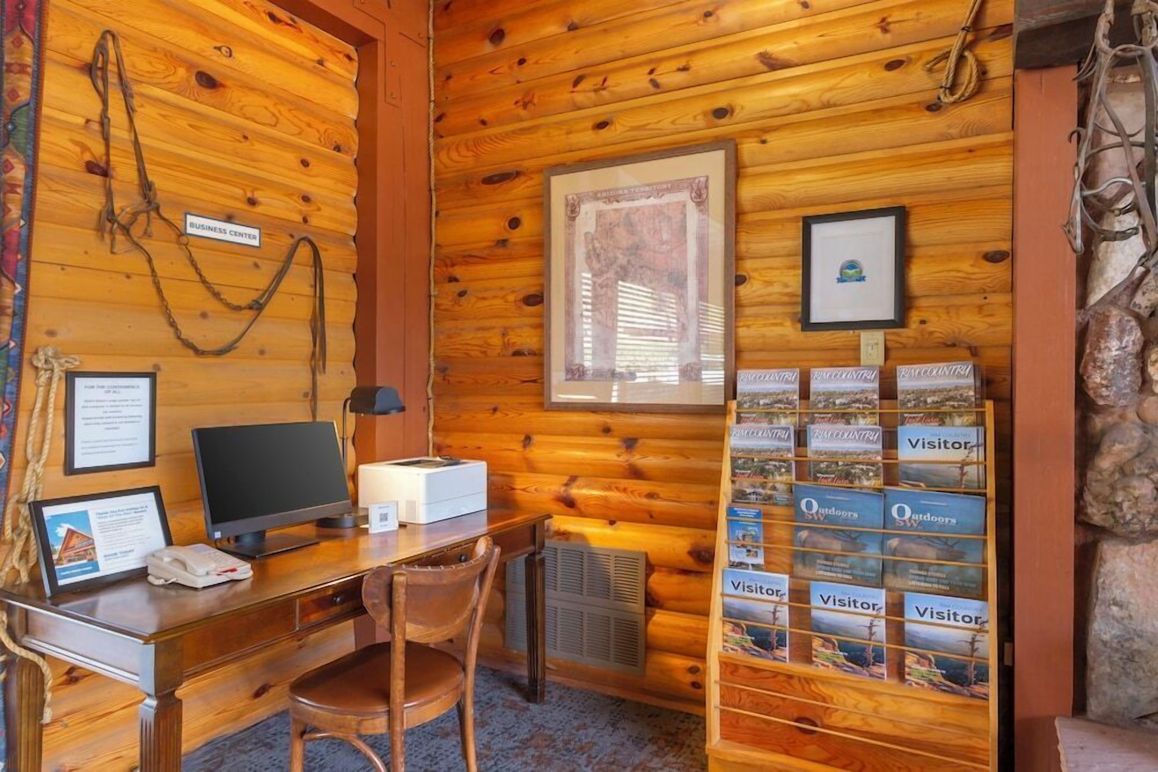 Una cabaña de madera con un escritorio, computadora y fotografías enmarcadas en las paredes.