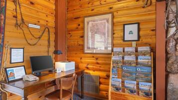 Una cabaña de madera con un escritorio, computadora y fotografías enmarcadas en las paredes.