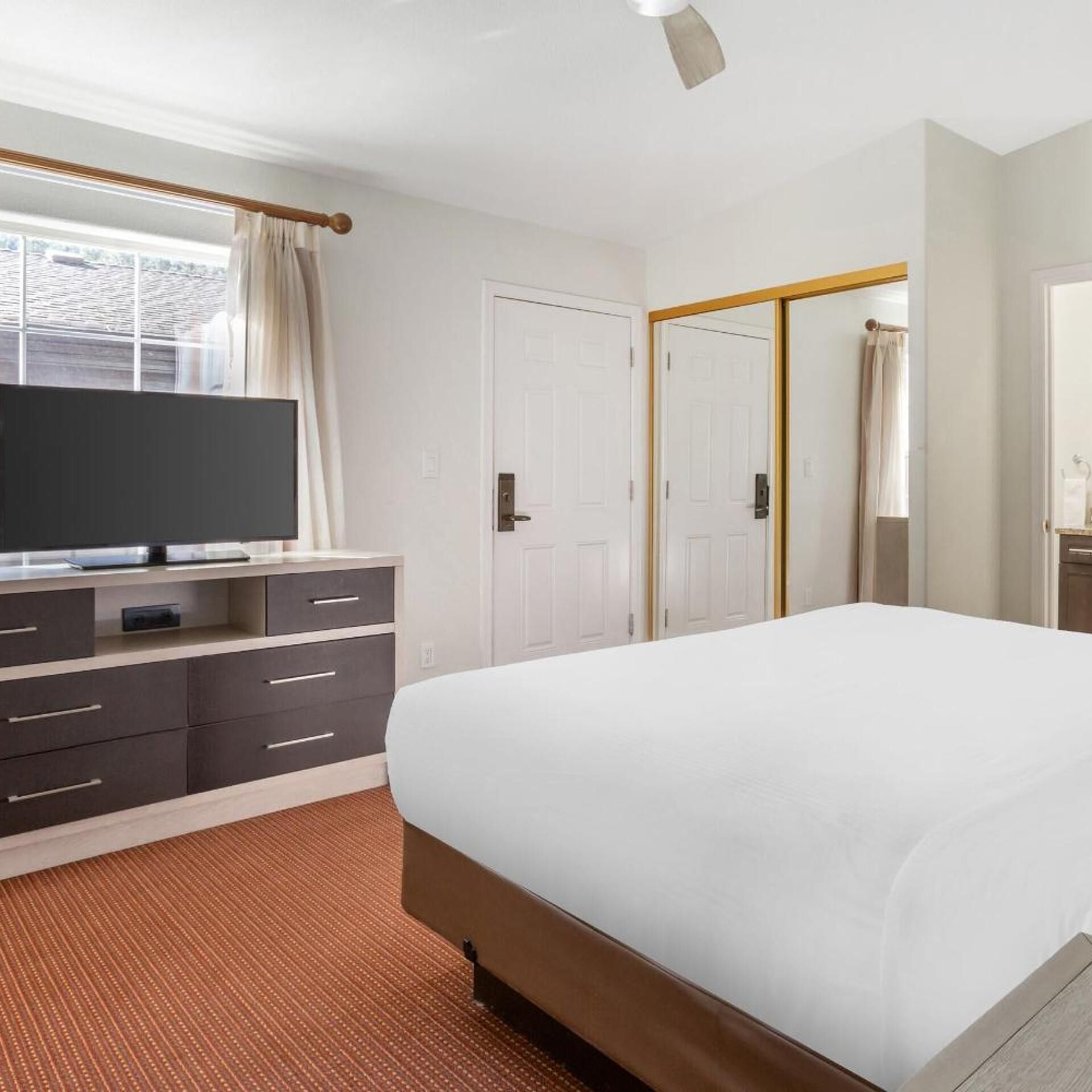 A hotel room with a bed, a television, a wardrobe, and a mirror.