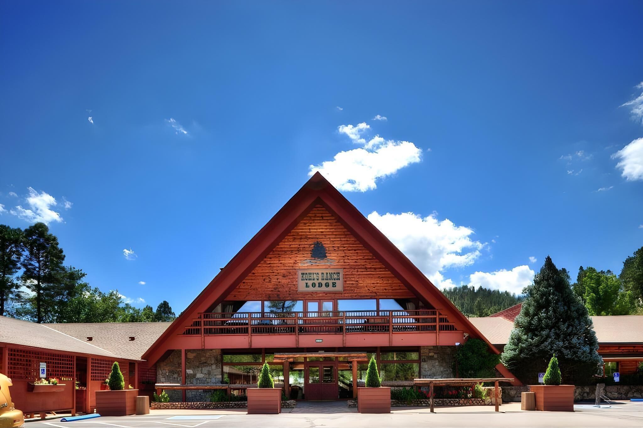 Un chalet triangulaire en bois, sur lequel est apposée une enseigne indiquant « Kohl’s Ranch Lodge ».