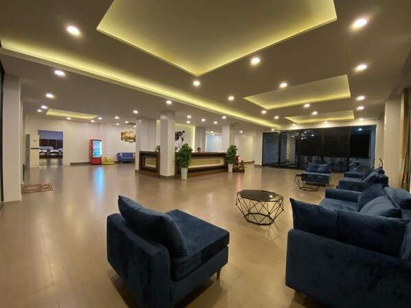 A spacious lobby with a reception desk, multiple seating areas, and a large screen. - Vang Vieng Topview Hotel (Vang Vieng)