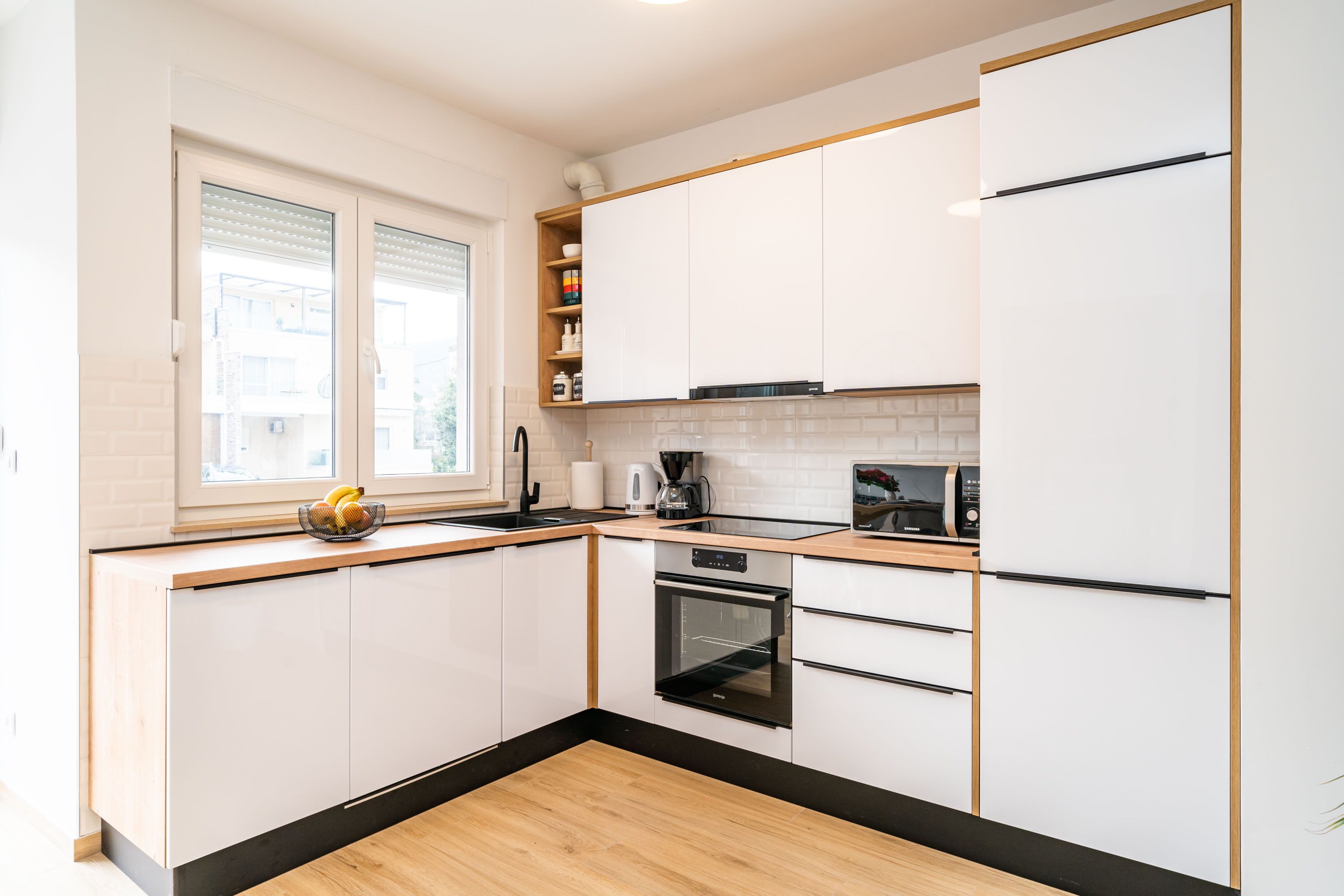 Een moderne keuken met witte kasten, een zwarte oven en een houten aanrecht.