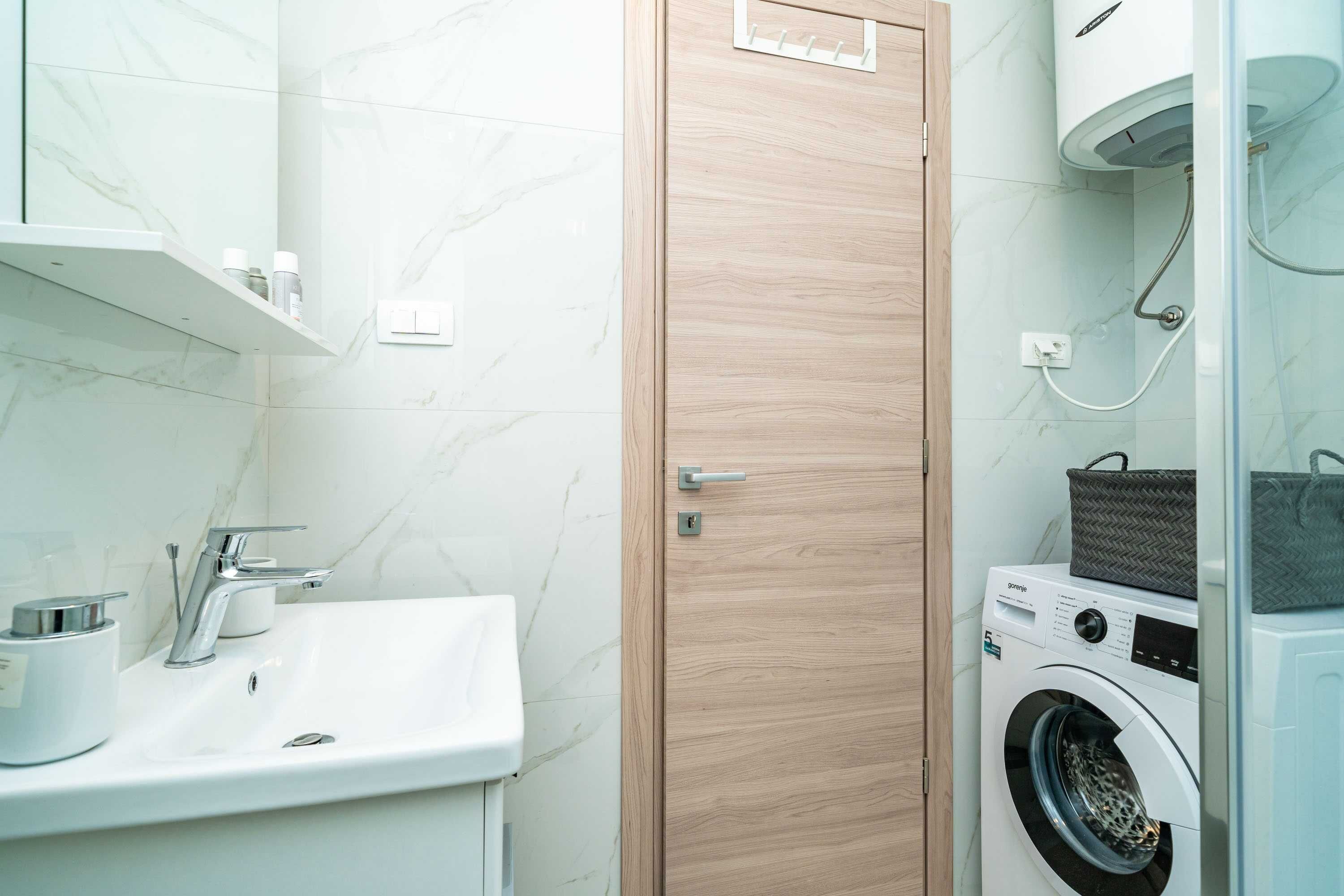A compact bathroom with a sink, mirror, and a washing machine.