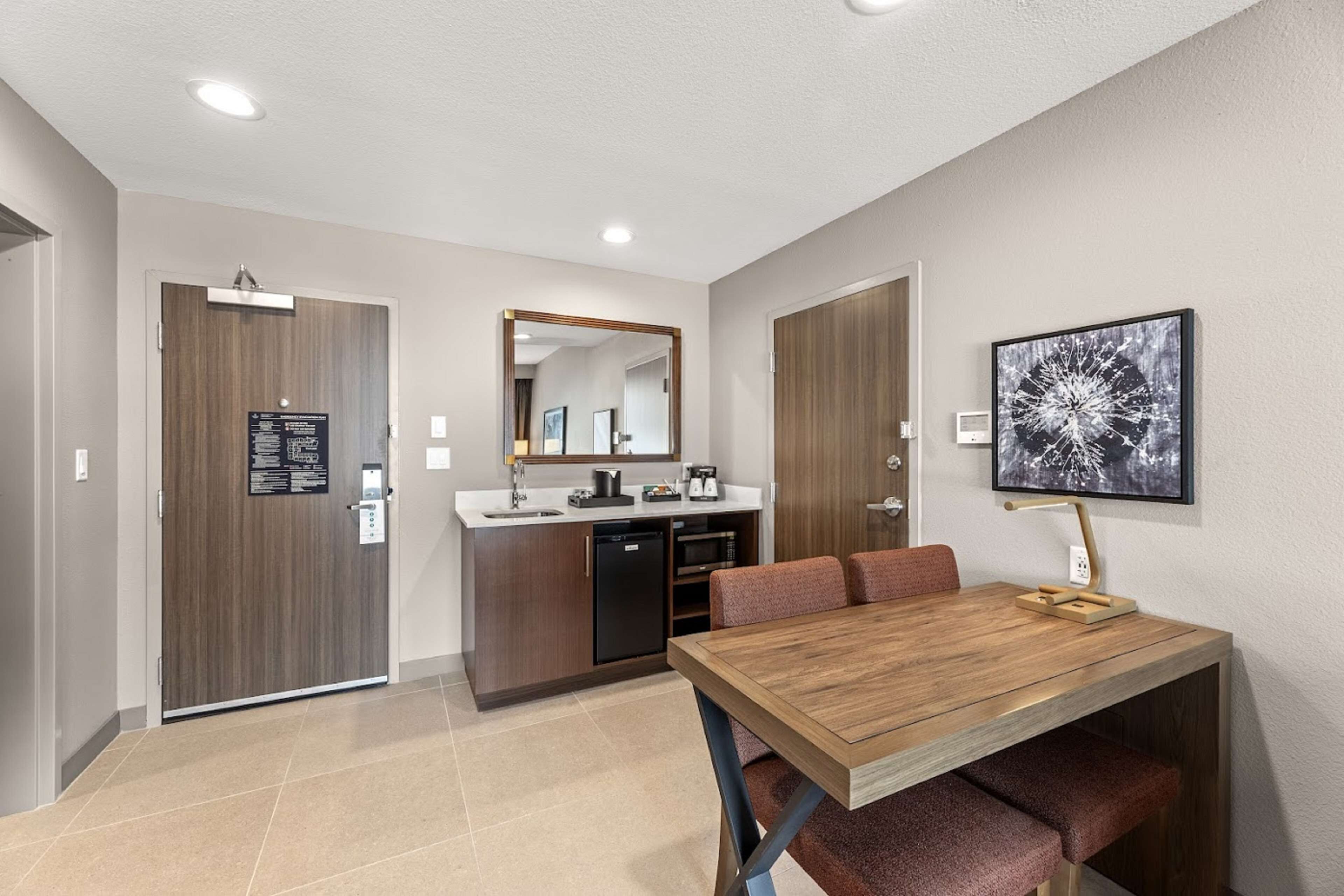 A modern kitchen with a wooden table and bench, a microwave, and a dishwasher.