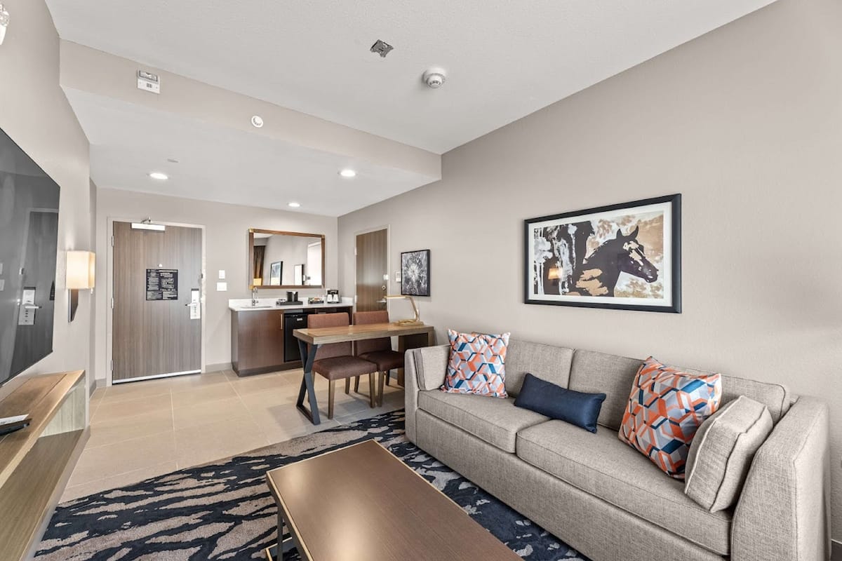 A modern living room with a sofa, coffee table, and a dining area with chairs and a table.