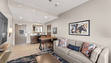 A modern living room with a sofa, coffee table, and a dining area with chairs and a table.