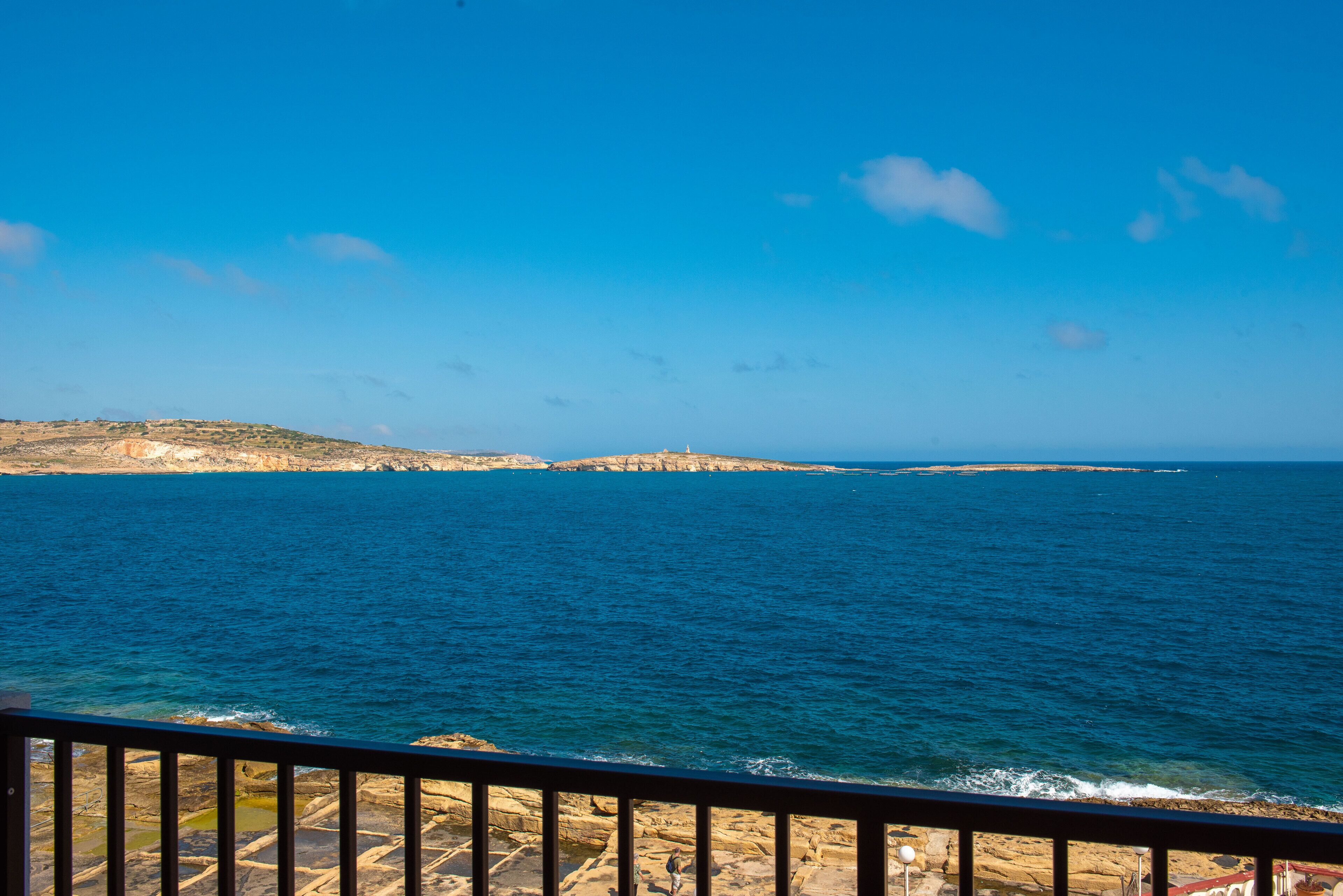 A coastal view with rocky terrain and a clear blue sky.