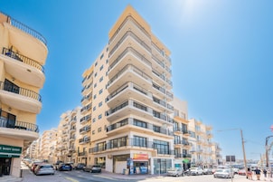 A multi-story building with balconies, a body shop, and a restaurant on the ground floor.
