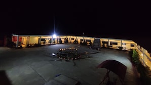 A hotel with a central courtyard, a large illuminated sign, and a statue.