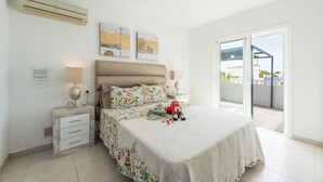 Une chambre à coucher avec un lit, des tables de chevet, une commode, une fenêtre et une vue sur l’extérieur.