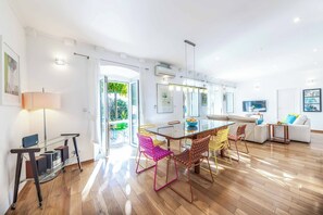 A modern living room with a glass dining table, colorful chairs, a sofa, and a TV. - Villa Salt Water - Four Bedroom Villa, Sleeps 8 (Dubrovnik)