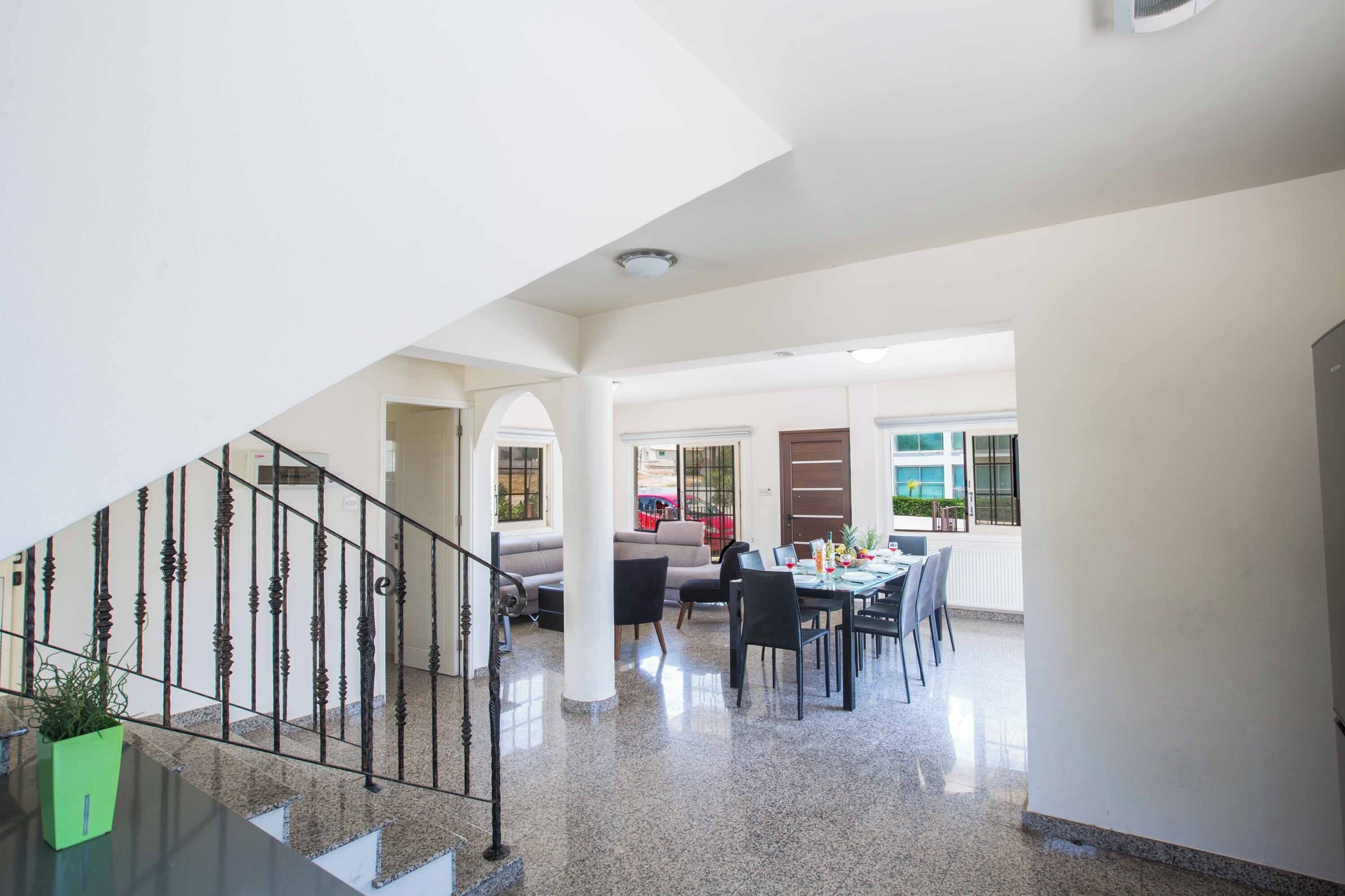 Uma sala de estar ampla com escada, mesa de jantar e sofá.