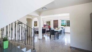 A spacious living area with a staircase, a dining table, and a sofa. - Villa Delfini 16 - Four Bedroom Villa, Sleeps 8 (Protaras)