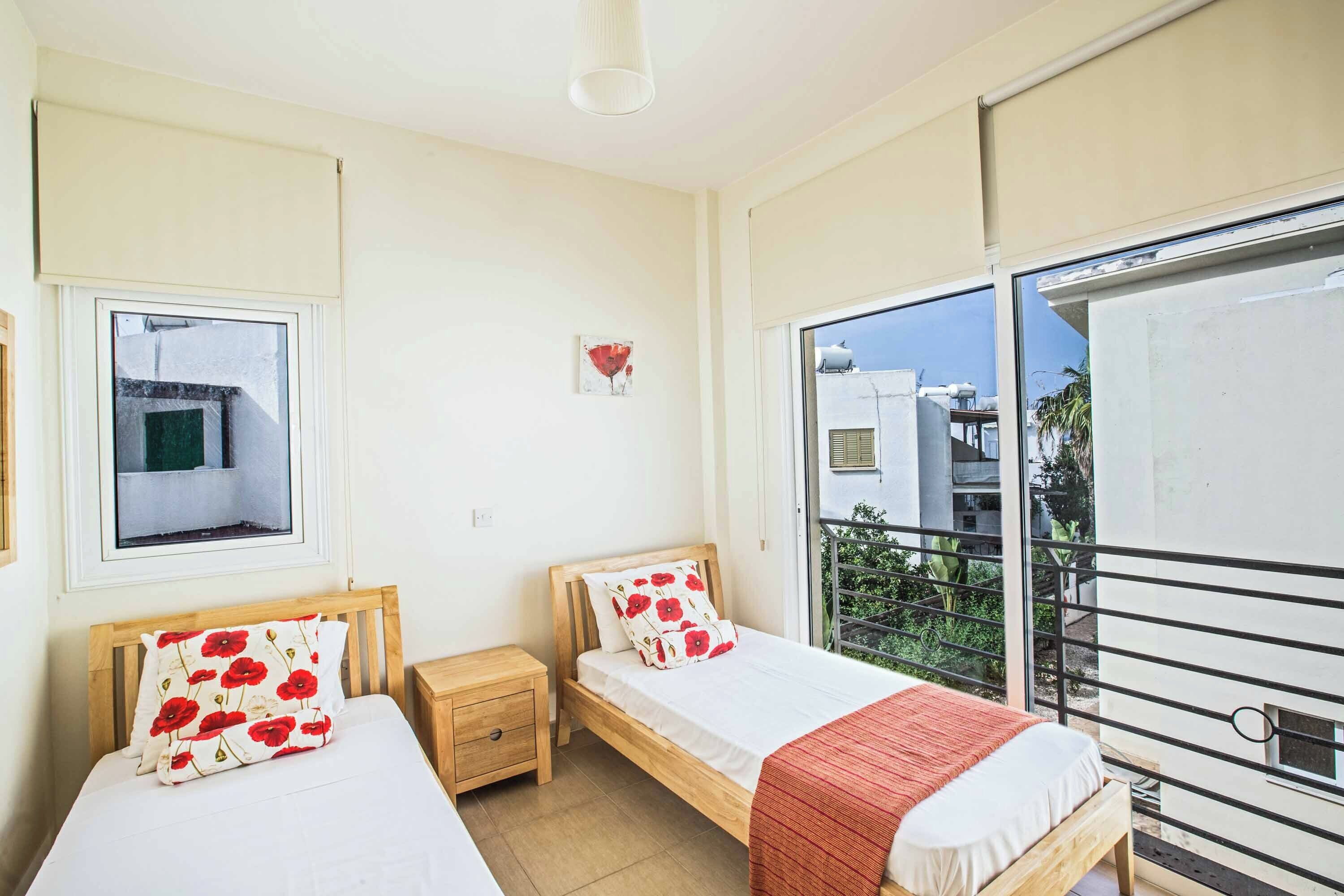 A bedroom with two beds, a window, and a balcony.