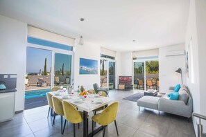A modern living room with a grey sofa, yellow chairs, and a dining area with a table set for two.
