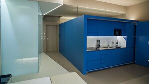 A modern kitchen with blue cabinets, a glass partition, and a stainless steel sink. - Royal Suite (Trapani)