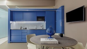 A modern kitchen with blue cabinets, a built-in microwave, and a flat-screen TV. - Royal Suite (Trapani)