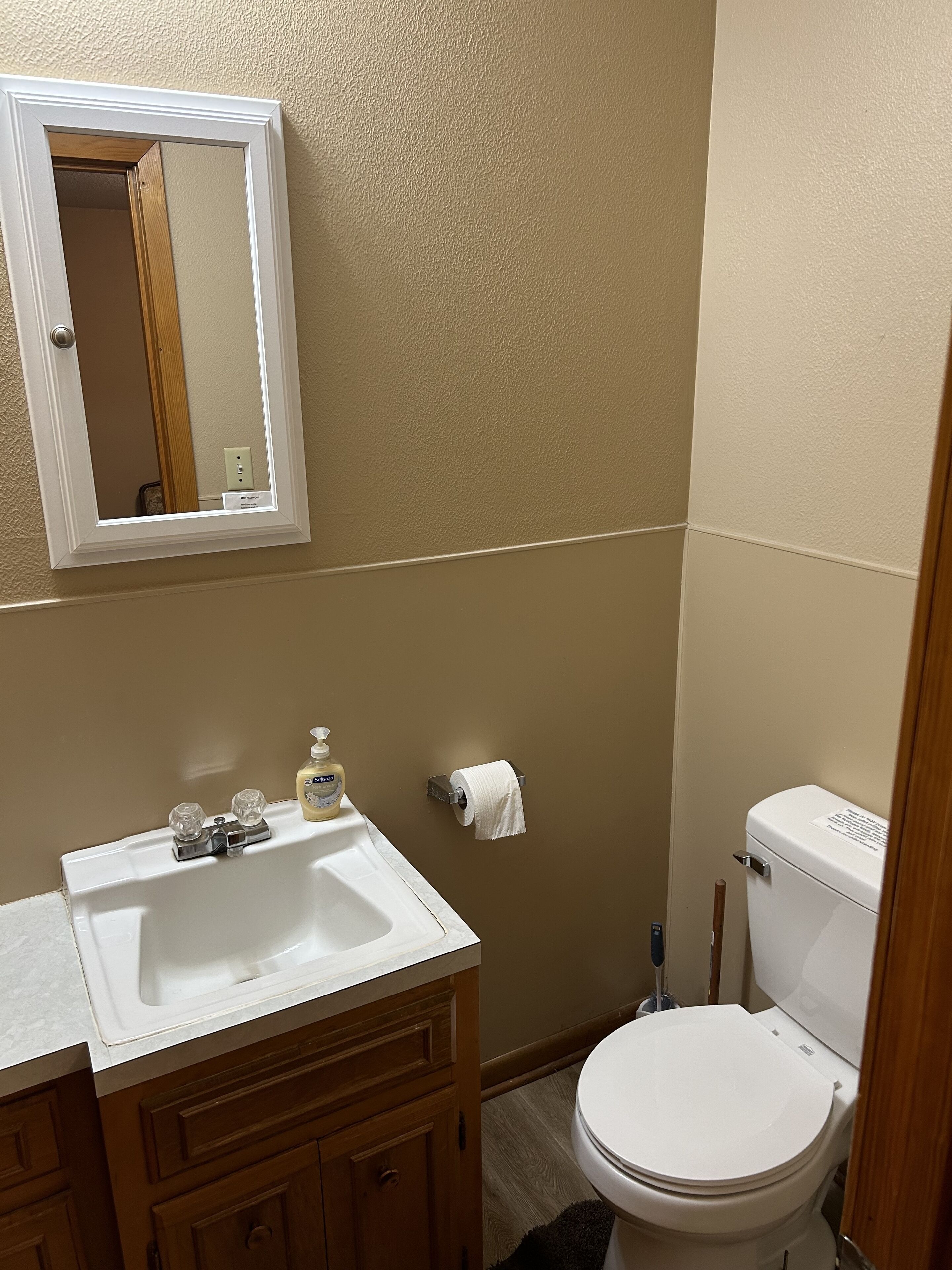 A bathroom with a white sink, mirror, and toilet.