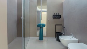 Et moderne badeværelse med en glasbrusekabine, en hvid vask og en blå pælevask.