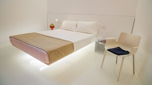 Une chambre à coucher au style minimaliste, avec un lit, une table de chevet et une chaise.