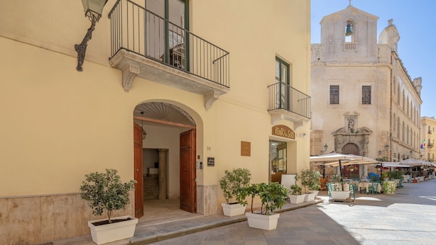 Un bâtiment doté d’un balcon, d’un clocher et d’un espace extérieur aménagé pour s’asseoir.
