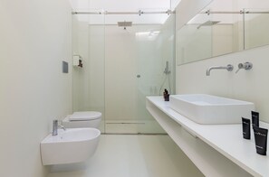 Une salle de bain moderne avec une douche à parois de verre, un lavabo blanc et un meuble-lavabo avec des articles de toilette.