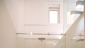 Une salle de bain moderne avec une douche à parois de verre, un lavabo blanc et un miroir au-dessus du lavabo.
