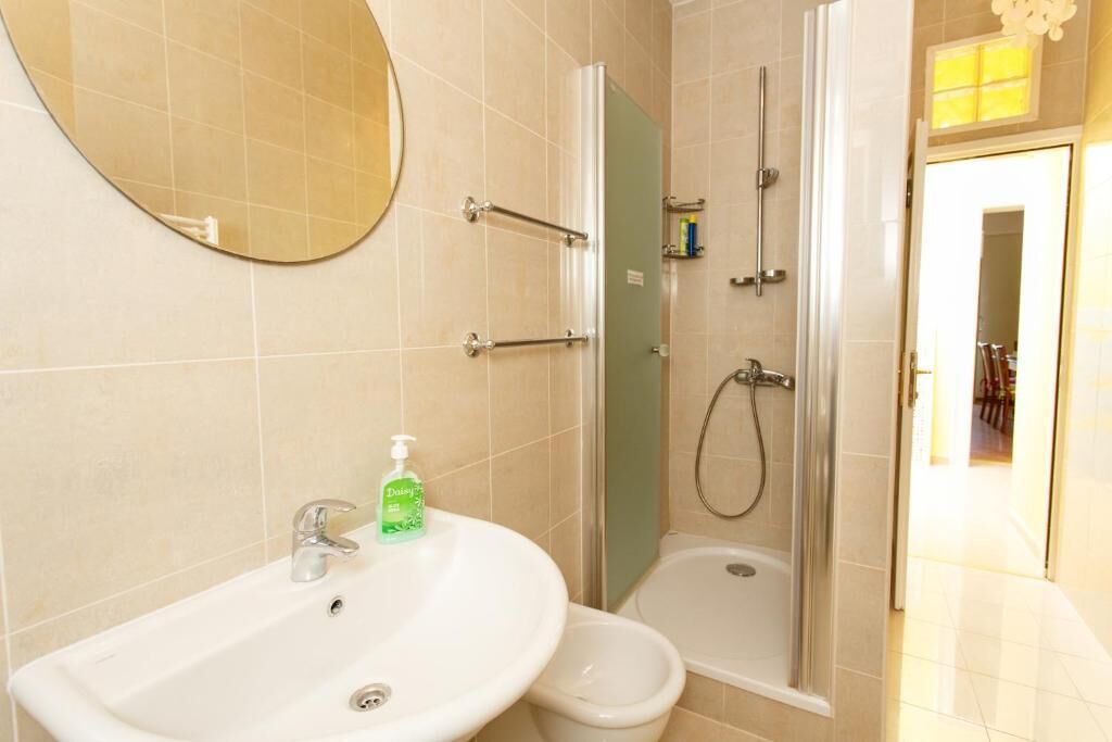 A bathroom with a sink, mirror, shower, and toilet.