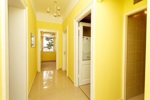 A hallway with yellow walls and a white door leading to a laundry area.