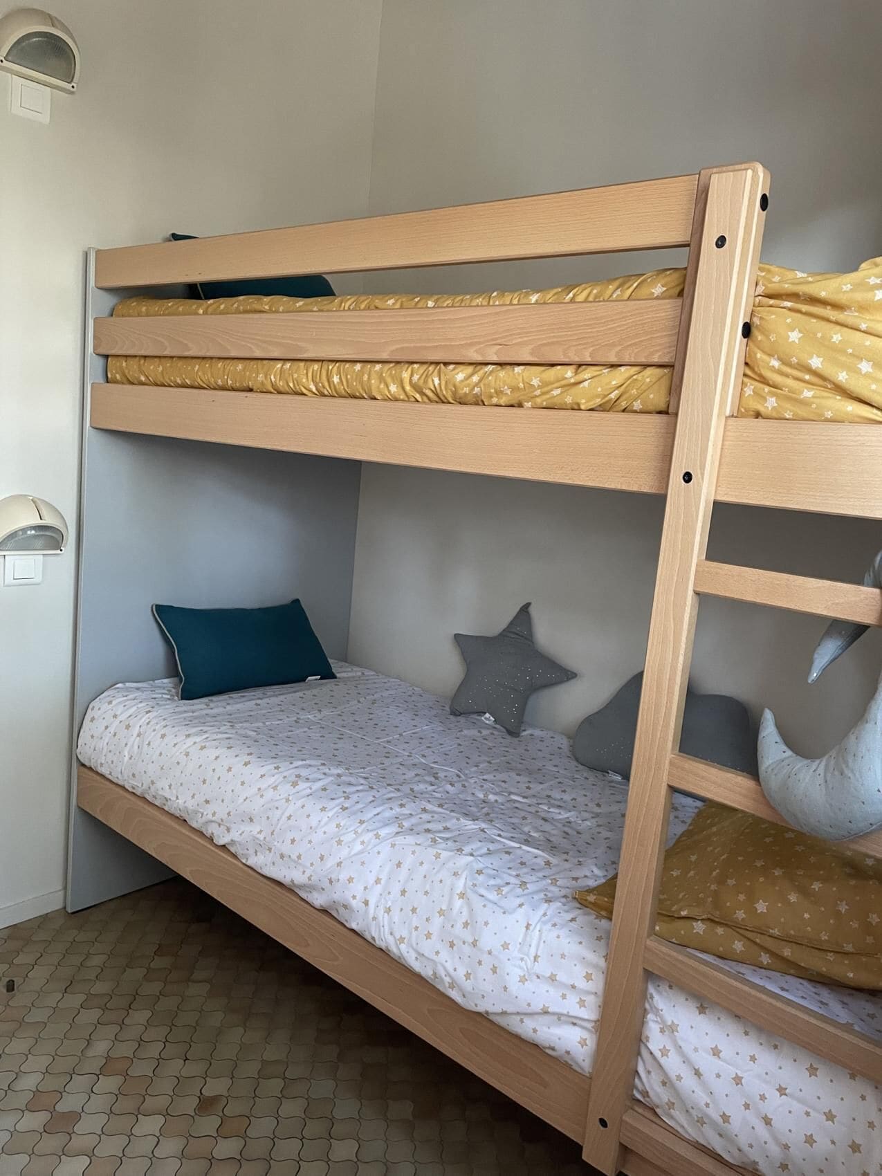 Letto a castello con un letto inferiore e un letto superiore, entrambi con biancheria a tema stelle.