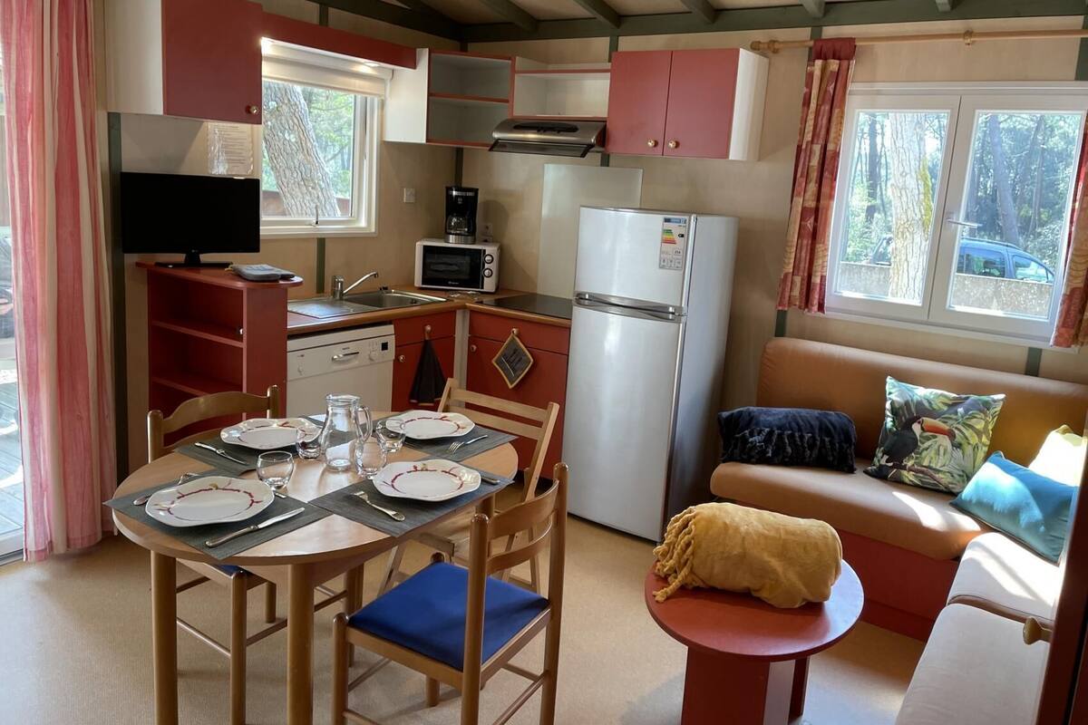 Eine kleine Küche mit Essbereich, einem Kühlschrank, einer Mikrowelle und einem Fernseher.