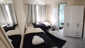 Habitació d'hotel amb dos llits, un armari i un ventilador.