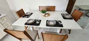 A dining table set with plates, glasses, and cutlery, surrounded by wooden chairs. - apartamento funcional  (Cascavel)