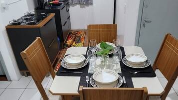Een eethoek met een tafel gedekt voor vier personen, een keuken met een gasfornuis en een koelkast.