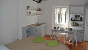 A compact room with a bed, a small kitchenette, and a dining area.
