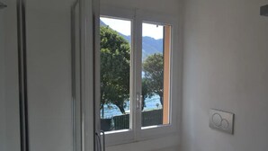 A bathroom with a window, a radiator, and a light switch.