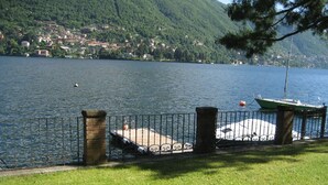 A lakeside view with a dock, a boat, and a grassy area.