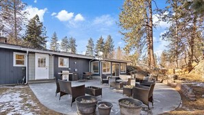 Eine überdachte Terrasse im Freien mit Sitzgelegenheiten, einem Grill und einer Feuerstelle.