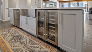 Eine moderne Küche mit Edelstahlgeräten, einem gemusterten Teppich und einer Holzbeschichtung an der Decke.