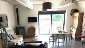 Una sala de estar con un sofá, una mesa con un florero, un televisor y una chimenea.